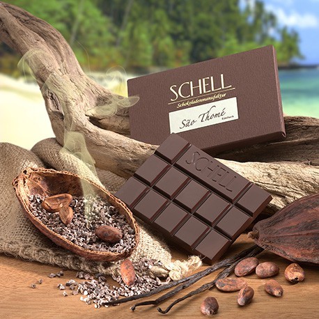 Die Sao Thomé Schokolade in der Verpackung lehnt an ein geschwungenes Holz, darunter befindet sich die unverpackte Schokolade und eine mit Kakaobohnen gefüllte Kakaoschote, Rechts von den Schokoladen liegt eine Kakaoschote und Vanilleschoten